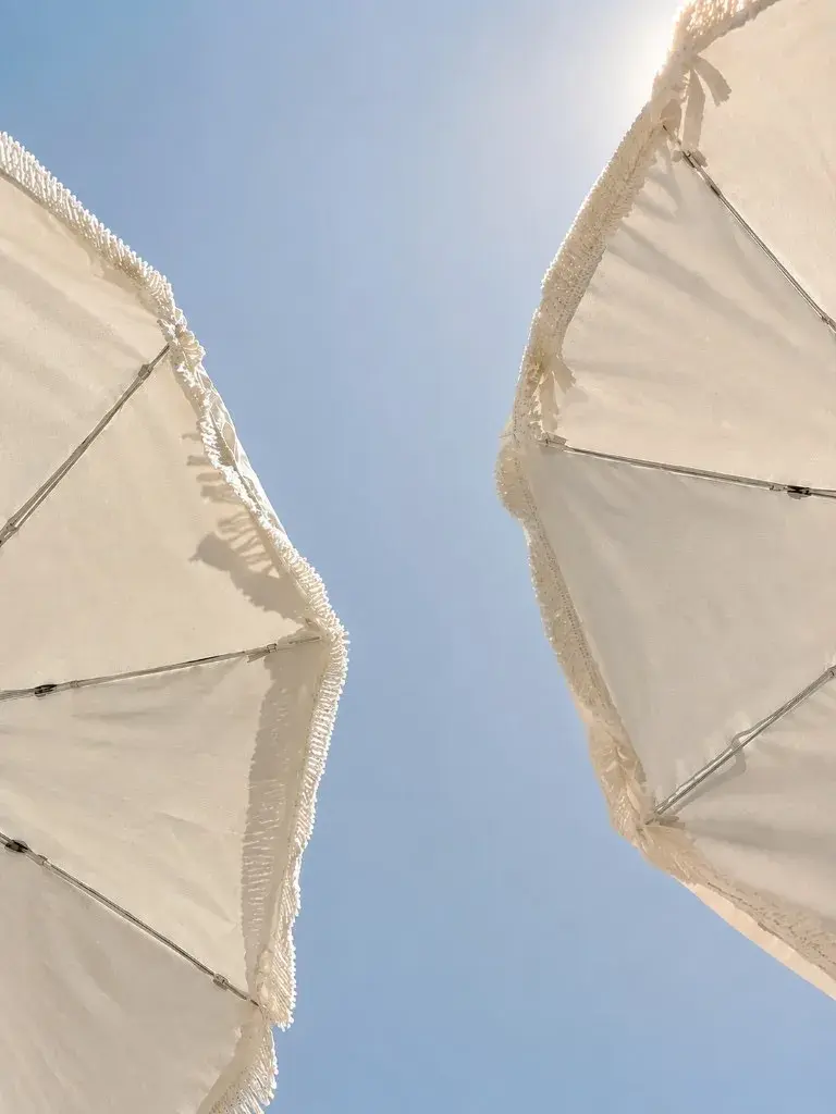 Fringed beach parasols against a clear summer sky